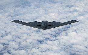 A B-2 stealth bomber flies above clouds.