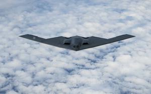 A B-2 stealth bomber flies above clouds.