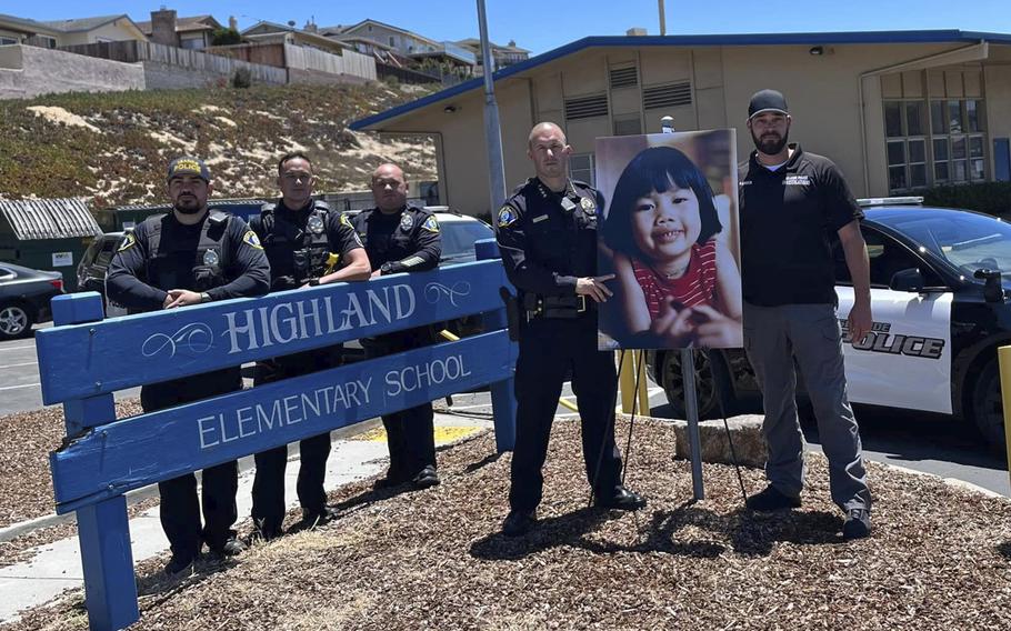 Police pose in front of an elementary school with a poster of a young girl.