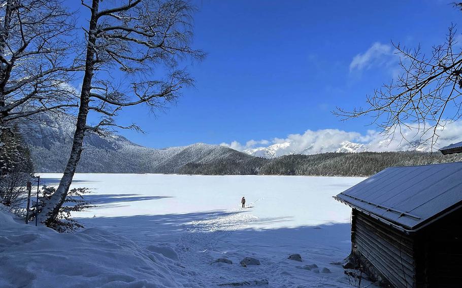 A person walks across the frozen Eibsee in Grainau, Germany on March 6, 2021. The lake nearby the Zugspitze, Germany's tallest mountain, has a gentle hiking trail surrounding it. 