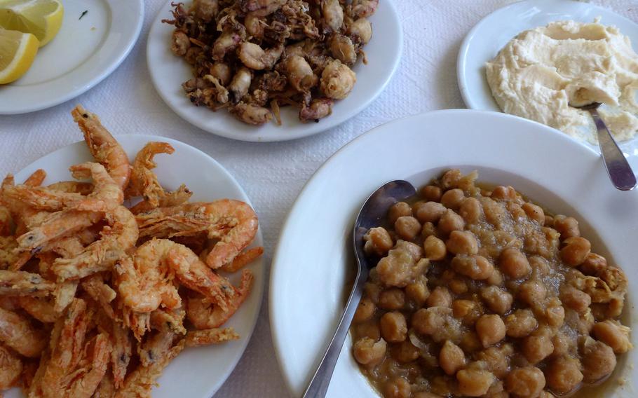 Many Greek islands have their own special dishes, like this chick pea stew, lower right served in a tavern in Parikia, Paros, along with shrimp, lower left; fried kalamari, center background; and a garlicky potato spread.
