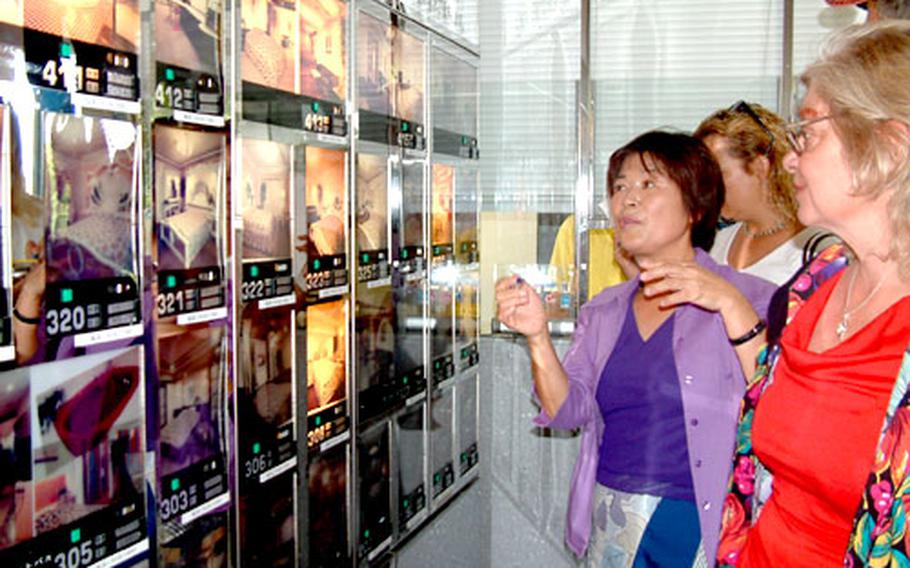 Setsuko Inafuku shows a tour group from Kadena Air Base how to choose a room at the Mint House, one of Okinawa’s many love hotels.