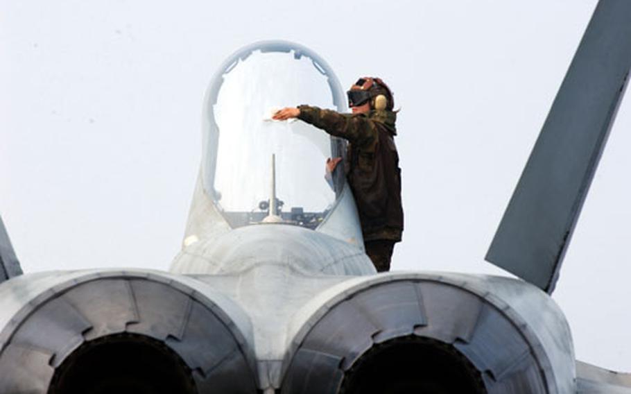 A plane captain cleans the canopy of an F/A-18C Hornet after its return from flight operations aboard USS Carl Vinson.