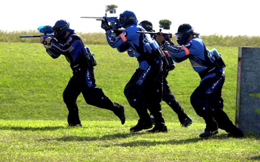 A team of speedball players sprints toward inflatable bunkers while firing at opponents during a tournament on Okinawa.