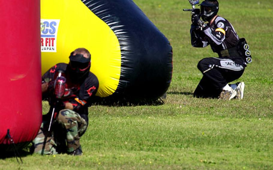 A defensive speedball player takes aim behind an inflatable bunker while an offensive teammate tries to move forward during a tournament on Okinawa.