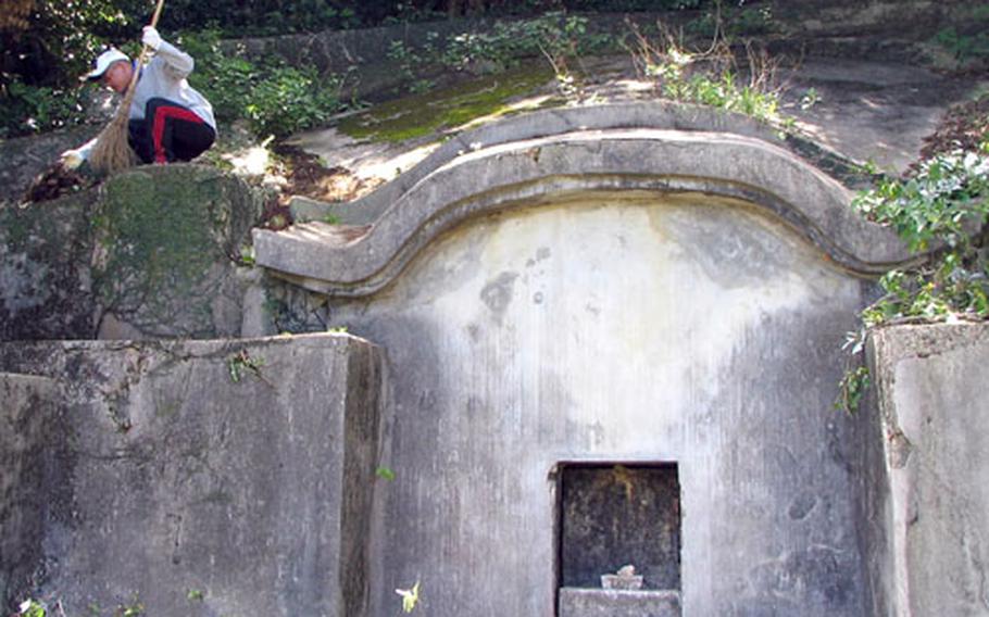 Isao Tsuha cleans brush from his family&#39;s centuries-old tomb on Okinawa in preparation for the annual shima festival, a time when families gather at the tombs of their ancestors for prayers, good food and a good time.