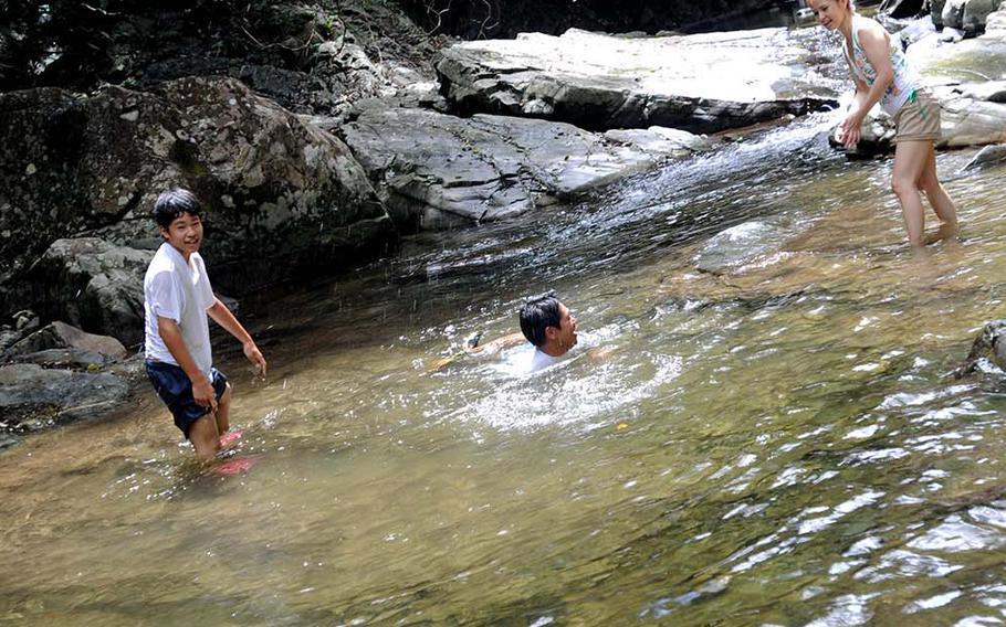 An Okinawan family plays downriver from the Hiji waterfall at Hiji Falls National Park, Okinawa.