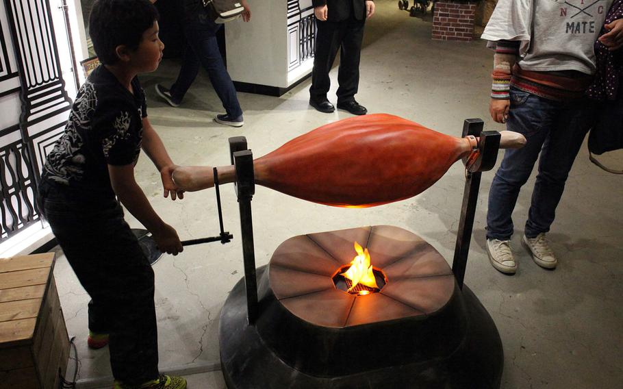 There are plenty of activities for children at Namco Namjatown, a large food-themed park inside Tokyo's Sunshine City shopping center. Here, a child roasts a fake piece of meat over a fake fire.