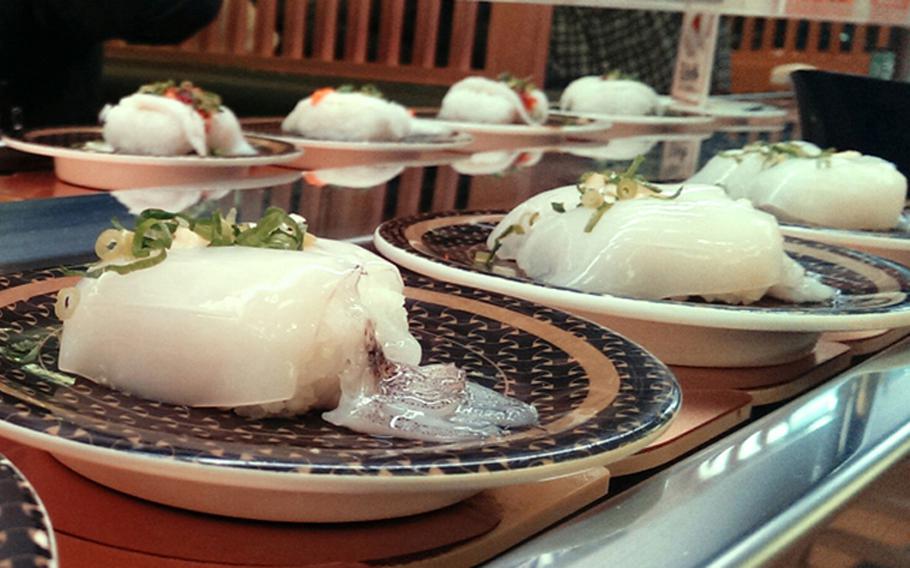 A garnished whole raw squid sushi called “sugata yariika” passes by a table at Hamazushi in Akishima. Even guests who don’t understand Japanese need no translation at a conveyor belt sushi restaurant.