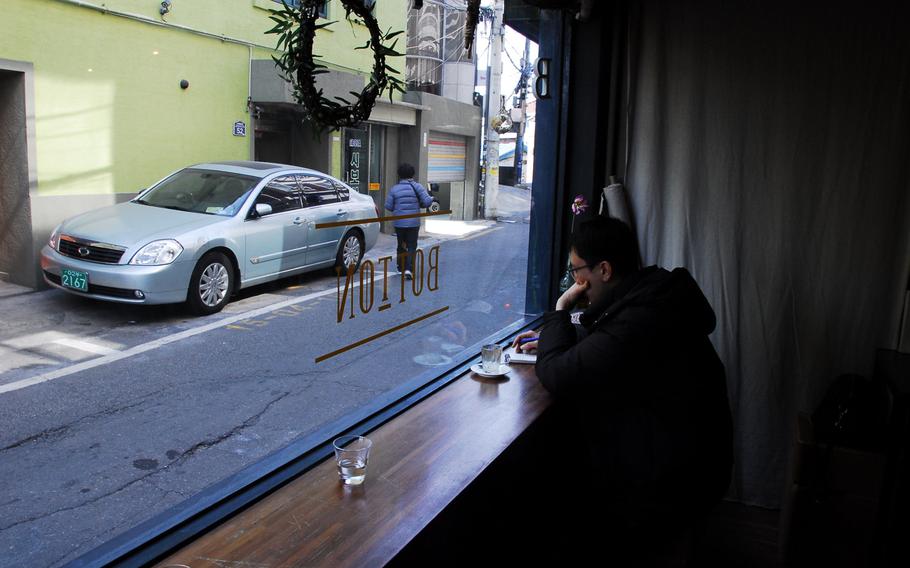 A customer at Botton sits at a window looking onto a narrow street that is home to a number of bars, coffee shops and restaurants in Seoul's Itaewon neighborhood. The area is populated with members of the U.S. military community, expat English teachers and Koreans