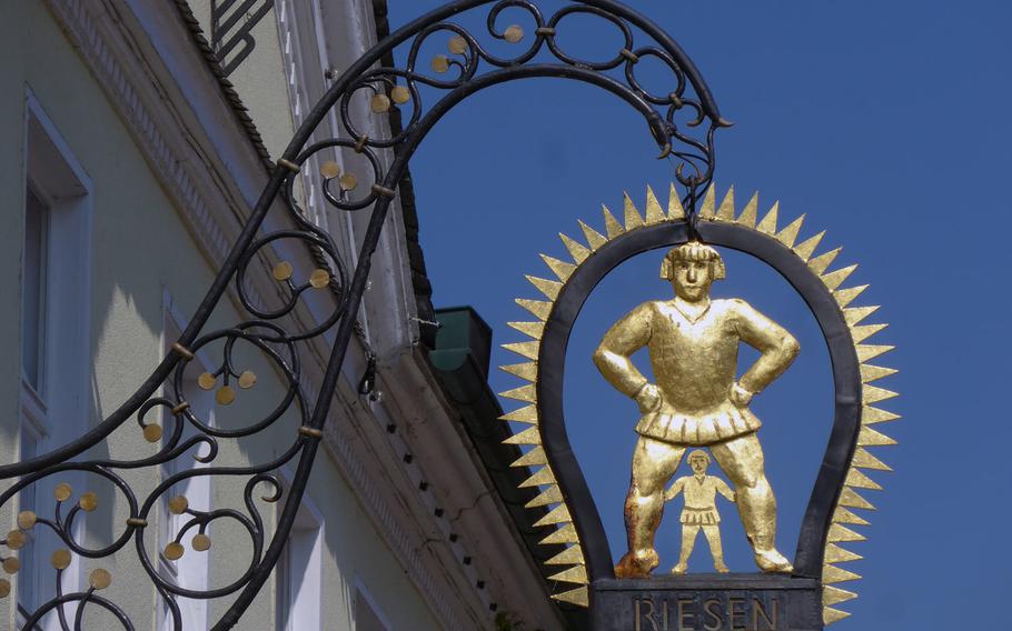 A sign featuring a giant and a mere mortal announces the Gasthaus zum Riesen (Riesen = giant), a restaurant and hotel on the Seligenstadt, Germany, marketplace.