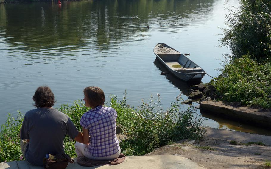 A couple relaxes on the bank of the Main River in Seligenstadt, Germany. At Seligenstadt, the river forms the border between the German states of Hessen and Bavaria.