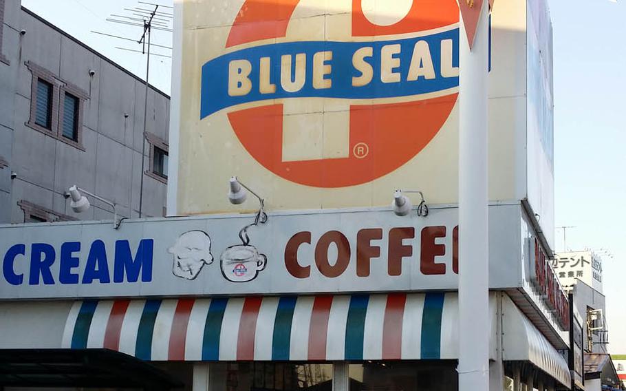Signs at the Blue Seal shop on Route 16 near Yokota Air Base, Japan, proclaim the company was "Born in America. Raised in Okinawa."