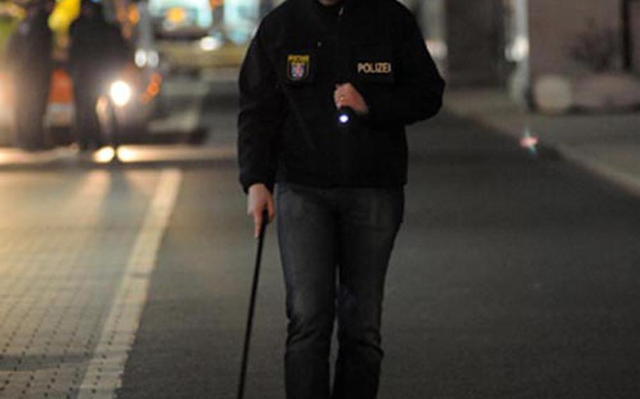 A German police crime scene investigator uses a metal detector and flashlight to search for clues after the shooting of four Americans at Frankfurt International Airport on Wednesday afternoon.