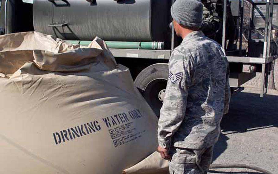 Airman 1st Class Cody Hoover (seated) and Staff Sgt. Alvin Pablo, from the 374th Civil Engineering Squadron on Yokota Air Base, fill a flexible water container with about 2,000 gallons of water, which will be used for shower stations set up by soldiers from Logistics Task Force 35 for displaced residents living at the Ono Civic Center shelter in Higashimatsushima, Japan. Pablo said they transport about 20,000 gallons of water to the site each day.