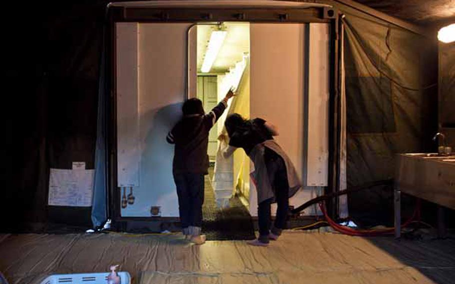 Kiroko Abe, 42, (left) and Yukari Kaimura, 39, displaced residents living at the Ono Civic Center shelter in Higashimatsushima, Japan, look at the shower facilities set up by soldiers from Logistics Task Force 35. The Army constructed two shower tents holding 24 showers and 12 sinks total.