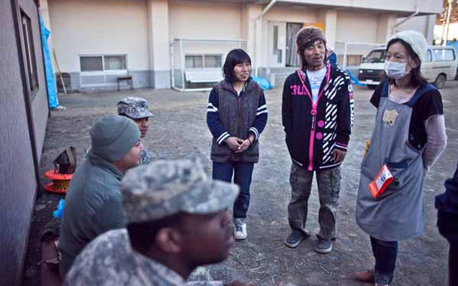 Displaced residents from the Ono Civic Center shelter in Higashimatsushima, Japan, talk with soldiers from Logistics Task Force 35, who spent the afternoon constructing two shower units for the residents.