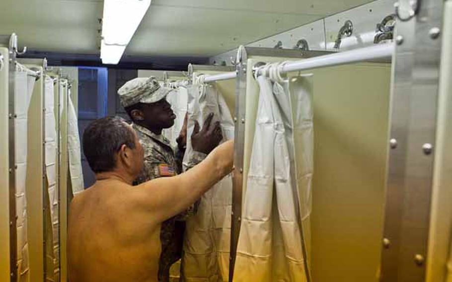 Staff Sgt. Jason Schriner, 28, assists a displaced resident living at the Ono Civic Center shelter in Higashimatsushima, Japan, with operating the shower. Soldiers from Logistics Task Force 35 constructed two shower tents holding 24 showers and 12 sinks total.