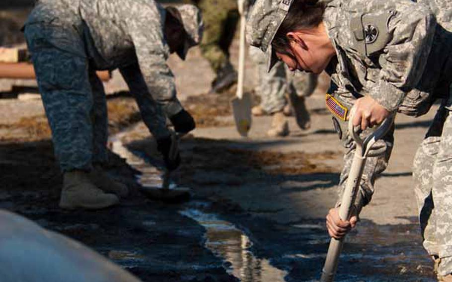 Soldiers from Logistics Task Force 35, along with Japan Self-Defense Force troops, work to dig a trench for run-off water from the shower units they set up near the Ono Civic Center in Higashimatsushima, Japan.  