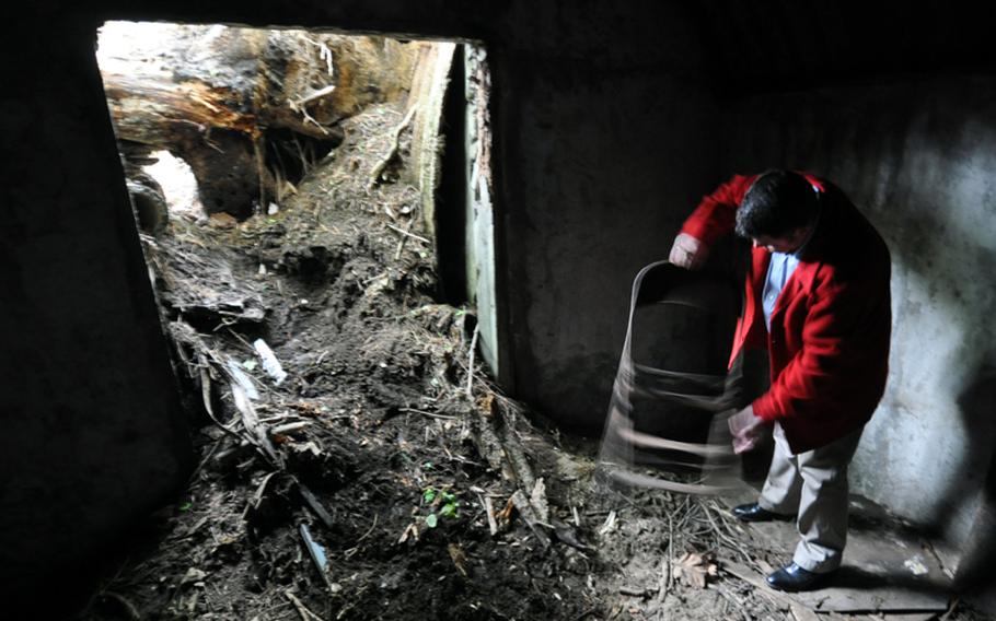 Richard Clark, 35th Fighter Wing historian, picks up an old folding chair that was abandoned in what is believed to be a World War II-era, Japanese military bunker in the woods on Misawa Air Base, Japan. Old beer cans from the 1970s show that base troops had discovered the bunker years ago.