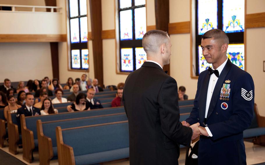 Air Force Tech. Sgt. Erwynn Umali, right, and his partner Will Behrens hold hands during their civil union ceremony Saturday at Joint Base McGuire-Dix-Lakehurst, the military base in Wrightstown, N.J. where Umali is stationed.