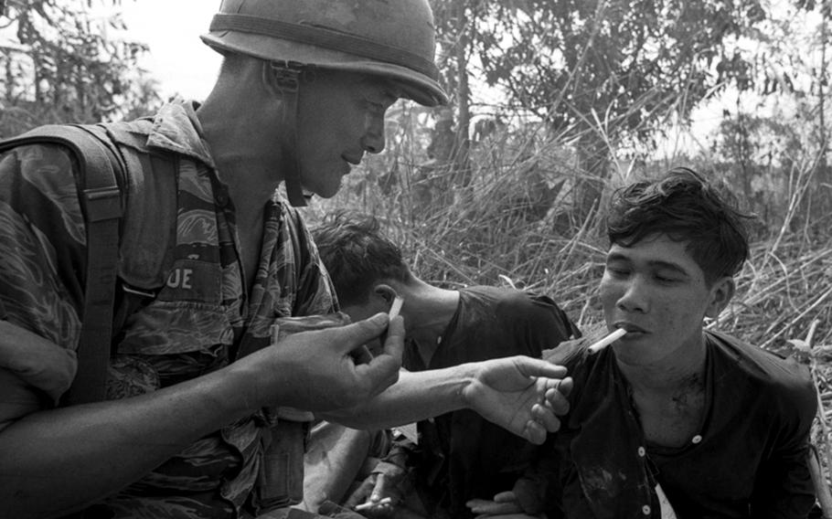 A South Vietnamese marine lights a cigarette for a Viet Cong prisoner.