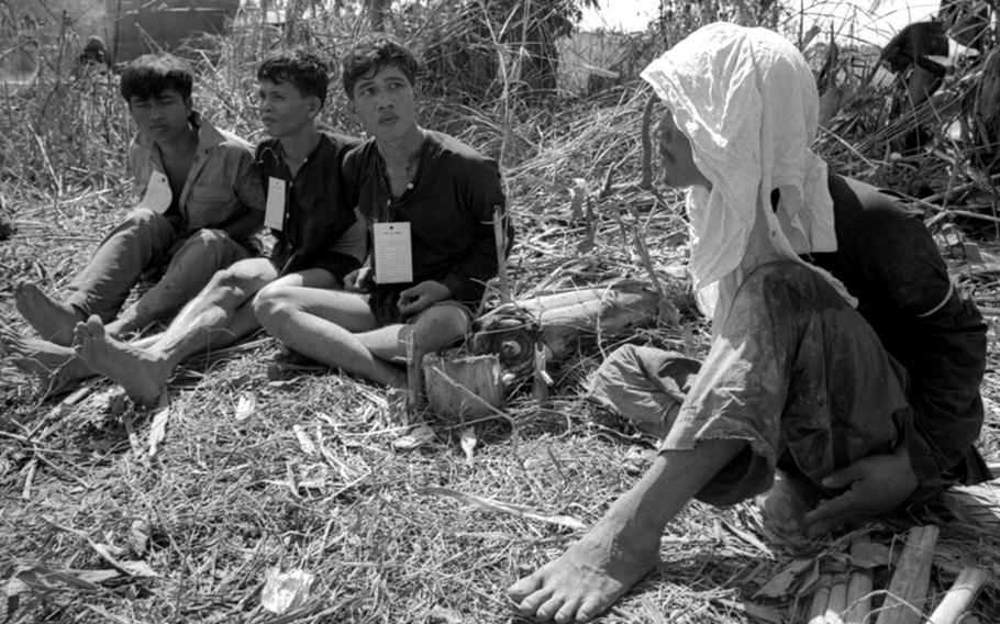 Viet Cong detainees, bound together, await transportation to an interrogation center.