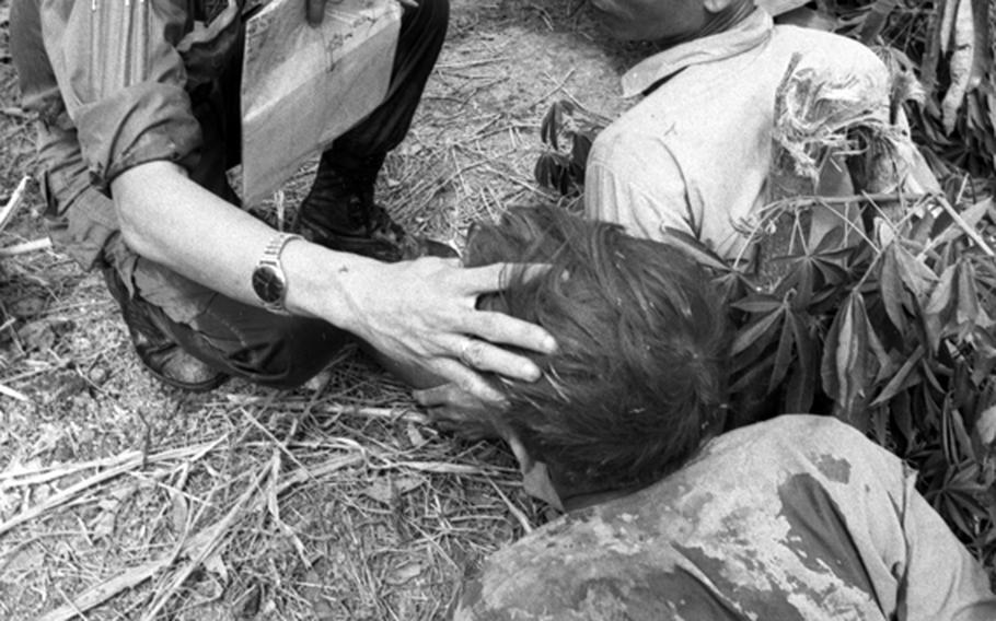 A South Vietnamese marine checks the condition of Viet Cong prisoners awaiting a move to an interrogation center.