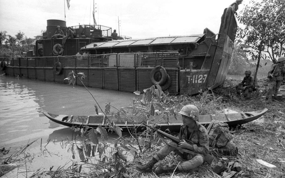 A marine from the 5th Vietnamese Marine Division poses next to a small Viet Cong boat on the banks of the My Tho River, 65 miles southwest of Saigon. In the background is an armored troop carrier.