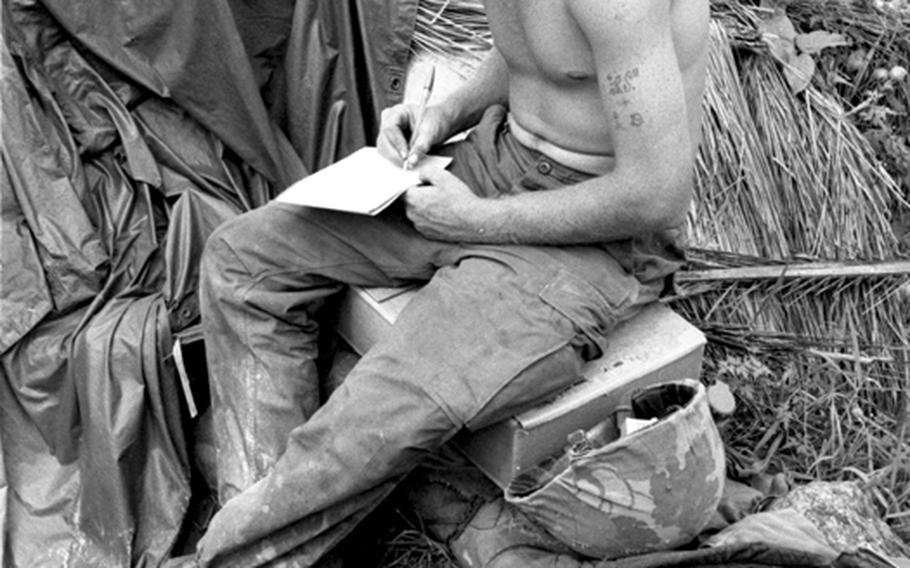 Pfc. Roger Spradley of Stuart, Fla., and E Company, 2nd Battalion, 26th Marines, writes home during a break from guarding Seabees working on the bridge.