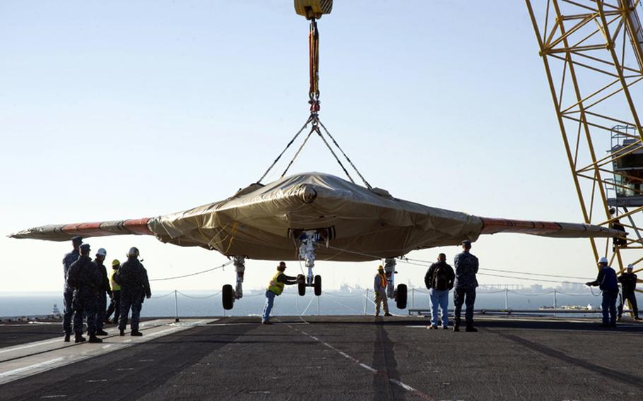 U.S. Navy Sailors assist in loading the X-47B Unmanned Combat Air System (UCAS) demonstrator aboard the aircraft carrier USS Harry S. Truman (CVN 75) on Nov. 26, 2012.