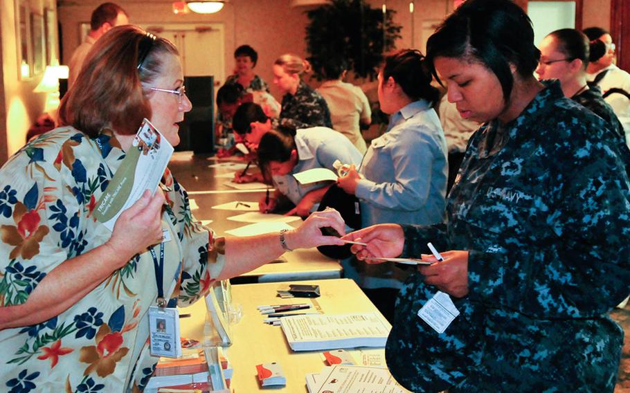 Janise Wilcox, a Tricare representative, hands out information packets on Tricare to a sailor at a Naval Station Norfolk pregnancy seminar in June, 2009. The seminar was open to all female and male sailors who have either had children or are contemplating starting families.