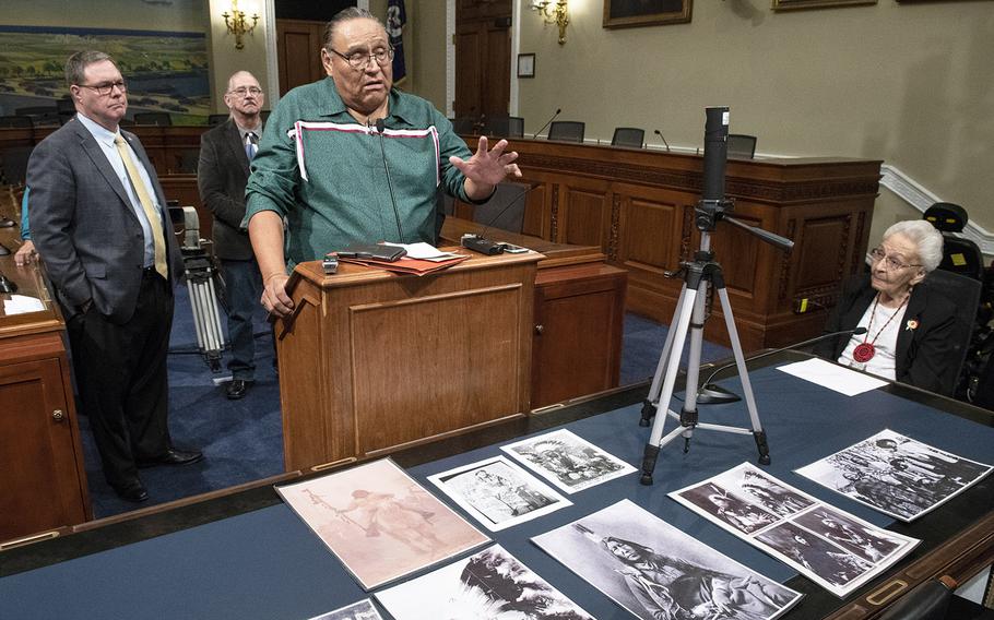 With ancestral pictures in front of him, Manny Iron Hawk of the Cheyenne River Sioux Tribe speaks at a Capitol Hill press conference on the Remove the Stain Act on June 25, 2019. At left is Rep. Denny Heck, D-Wash., one of the bill's sponsors; behind them is Oliver "OJ" Semans, a Navy veteran and member of the Rosebud Sioux Tribe. At right is 99-year-old Marcella LeBeau, a member of the Cheyenne River Sioux Tribe who was a 1st lieutenant in the Army Nurse Corps during World War II. The bill would rescind the Medals of Honor awarded to soldiers involved in the 1890 Wounded Knee Massacre.