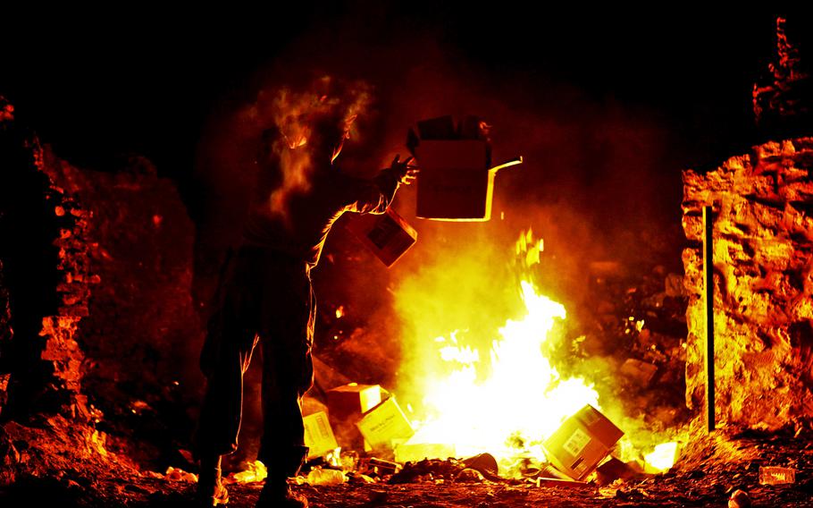 A Marine disposes of trash at the burn pit on Forward Operating Base Zeebrudge in Afghanistan's Helmand province, March 6, 2013.