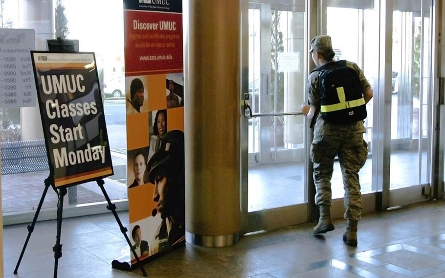 An airman walks past signs in an on-base shopping arcade advertising university classes due to start at Yokota Air Base, Japan, March 11, 2013.