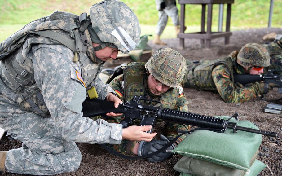 Sgt. Cesar Cobena, from 66th Military Intelligence, assists a German soldier in loading his M16 while at the Training Support Center Wackernheim Range in December, 2012.