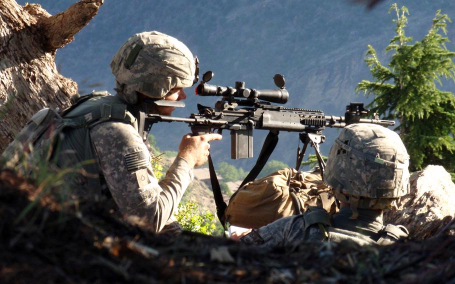 Spc. Ty M. Carter and Spc. Jonathan Adams, the Blue Platoon forward observer, look at the village of Kamdesh, Afghanistan, while on their first patrol out of Observation Point Fritsche, May 2009.