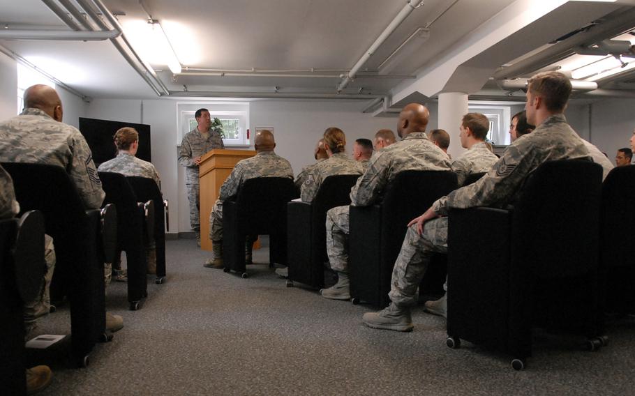 Staff members with the Air Force Deployment Transition Center at Ramstein Air Base, Germany, along with guests listen to Master Sgt. Corey Hancock talk about the history of the center during a ceremony Tuesday. The center was celebrating its third-year anniversay.