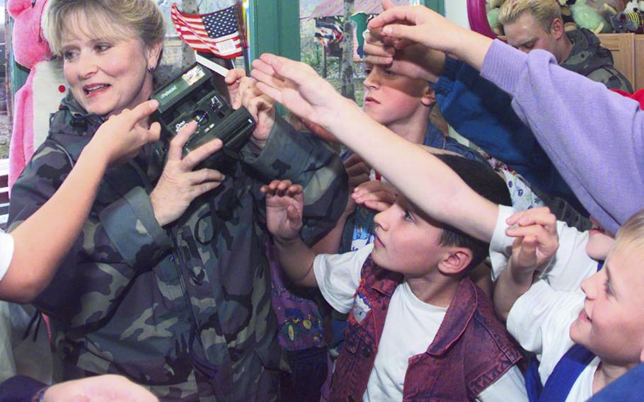 Capt. Debra Muhl, assigned to the 401st Expeditionary Air Base Group at Tuzla Air Base, passes out Polaroid pictures that she had just taken of the children at the Simin Han Center for Mothers and Children. The center houses 22 women and their children who lost their husbands and fathers during the Bosnian civil war.