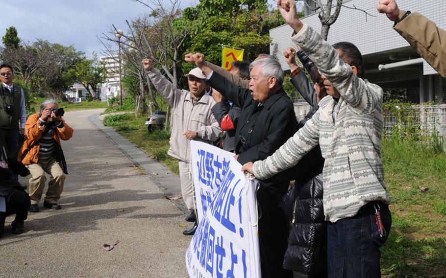 Protesters raise their fists outside the Naha District courts Wednesday, Jan. 15, 2014, in support of a lawsuit that would stop construction of a new air field on Marine Corps Base Camp Schwab. 