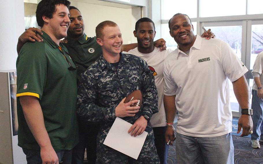 NFL players Greg Van Roten, Brad Jones, Justin Bethel and William Henderson take a photo with Petty Officer 2nd Class Eric Douglas from the USS George Washington after the Super Bowl Feb. 3. The players toured Yokosuka Naval Base to interact with sailors during the game.