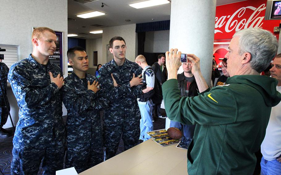 Packers head athletic trainer Pepper Burruss takes a photo of USS George Washington sailors Eric Douglas, Chan Saephanh and Justin Reynolds wearing Burruss' championship rings after the Super Bowl Feb. 3. Burruss and four NFL players visited Yokosuka Naval Base to interact with military and their families during the game.