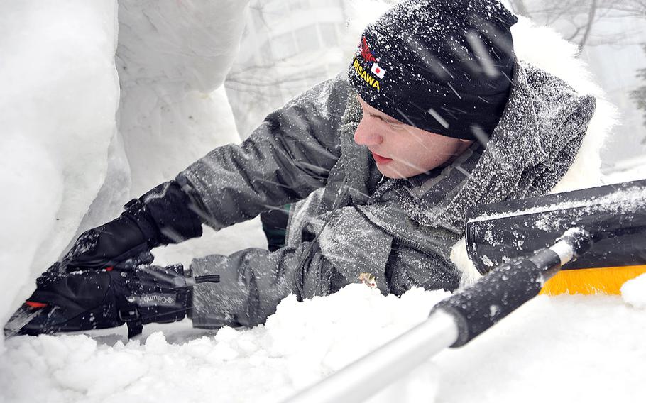 Seaman Andrew Handley, works through the driving snow as he shapes a portion of a snow sculpture, Jan. 31, 2014, at the 65th Annaul Sapporo Snow Festival in northern Japan. The team sculpted a 3-D version of the U.S. Navy Seabee's "Fighting Bee" logo.