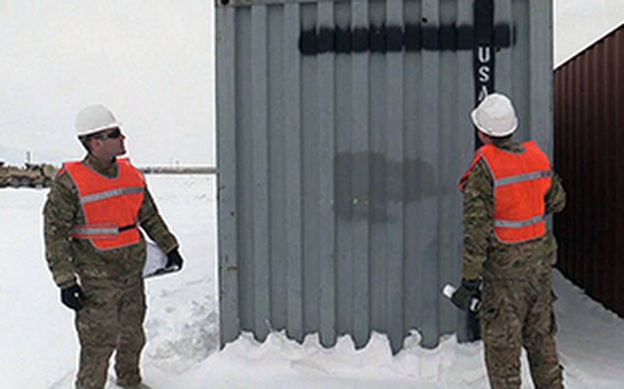 Chief Petty Officer Aaron Borg, with the U.S. Coast Guard Redeployment Assistance and Inspection Detachment team, and Petty Officer 2nd Class Michael Callinan, walk the perimeter of two shipping containers at Camp Marmal in Afghanistan in February 2014. They are determining whether the two containers are worthy to be shipped home, or scrapped and recycled. 