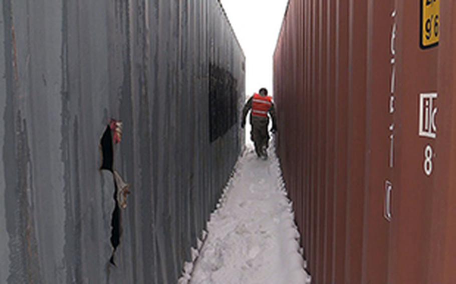 Chief Petty Officer Aaron Borg, with the U.S. Coast Guard Redeployment Assistance and Inspection Detachment team walks between two shipping containers in northern Afghanistan in February 2014. The team inspects the containers to determine if they are suitable for shipment home.