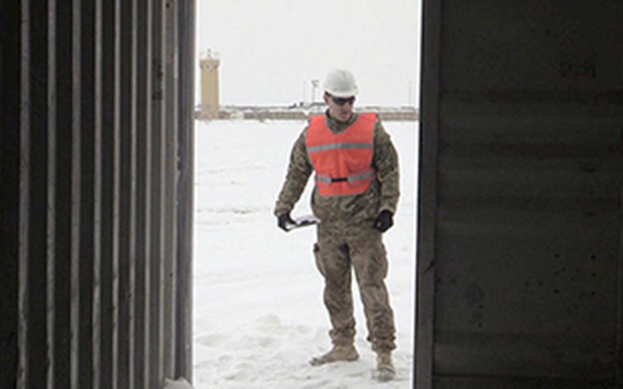 Coast Guard Petty Officer 2nd Class Michael Callinan inspects a U.S. Army Shipping container at Camp Marmal in Mazar-e-Sharif, Afghanistan, in February 2014. Callinan is a member of the U.S. Coast Guard's Redeployment Asistance and Inspection Detachment team.