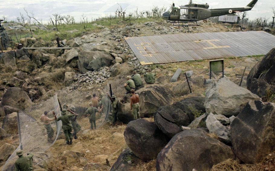 Soldiers work on defenses as a helicopter lands atop Nui Ba Den (Black Virgin Mountain), Vietnam, in 1969.