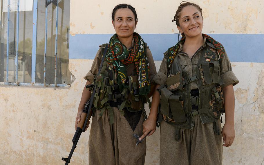 Felice Budak, 24, left, and Zekia Karhan, 26, react to a bit of friendly ribbing from a couple of fellow male fighters while posing for a portrait in Makhmur, Iraq, on Aug. 23, 2014. Karhan and Budak are guerrillas in the Kurdistan Workers' Party.