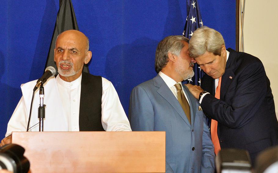Afghan presidential candidate Ashraf Ghani speaks during a news conference on Friday, Aug. 8, 2014,  in Kabul as rival candidate Abdullah Abdullah, center, talks to Secretary of State John Kerry. On Thursday, Sept. 18, 2014, Afghan officials said differences over releasing results of the disputed presidential election are holding up final agreement on a power-sharing deal between the two candidates to succeed President Hamid Karzai.