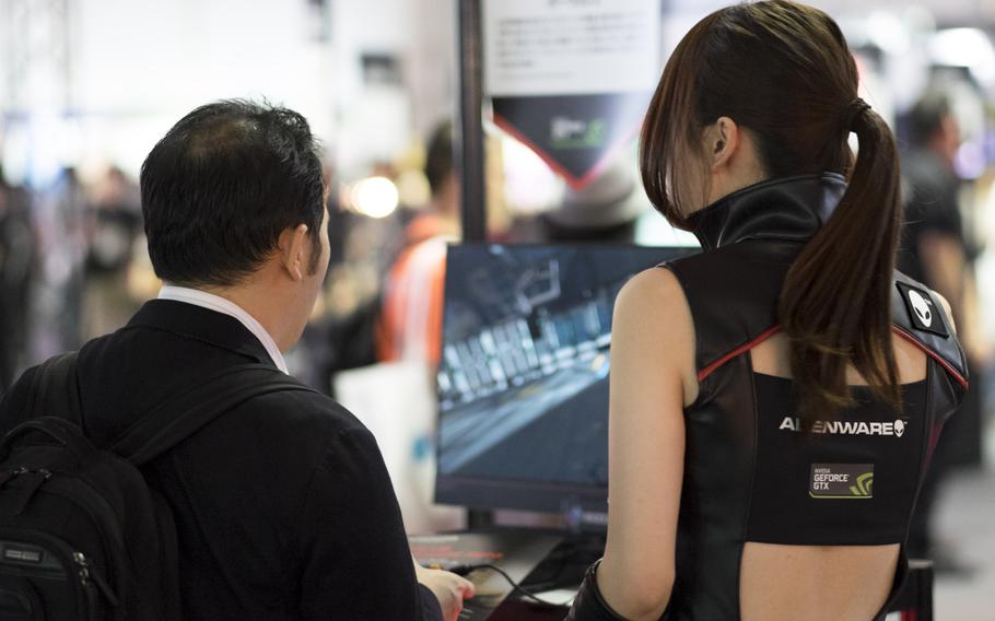 A model for Alienware explains her company's new streaming game console, Alpha, to a game tester at the Tokyo Game Show Sept. 18, 2014, in Maruhaki, Japan.